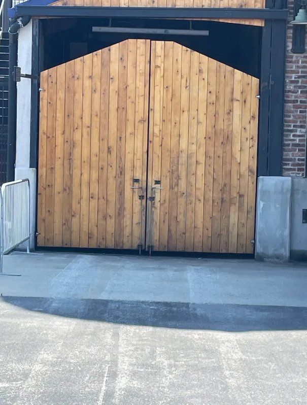 Large wooden double gate with arched top in a brick industrial entryway