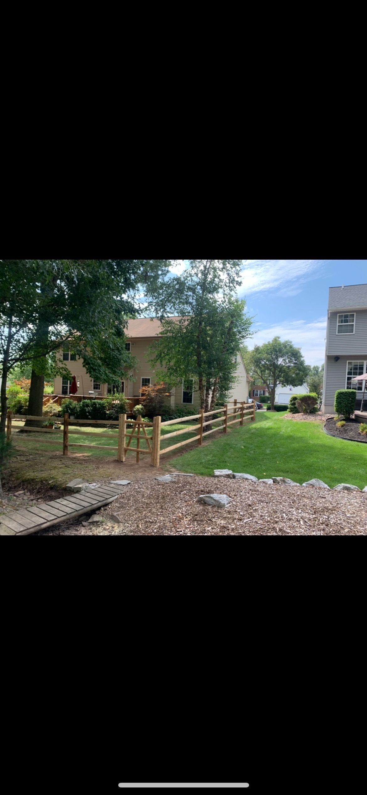 Garden path leading to a small house with trees and green lawn under a cloudy sky