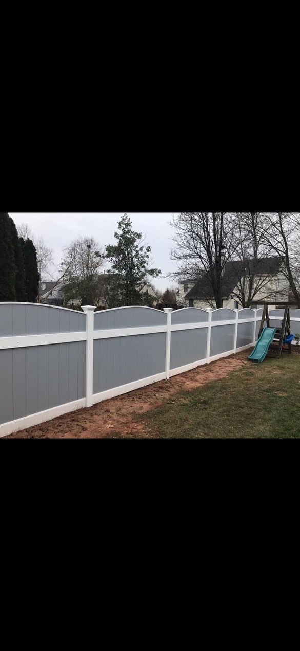 White vinyl fence along a yard with bare trees and a small blue object near the right side.