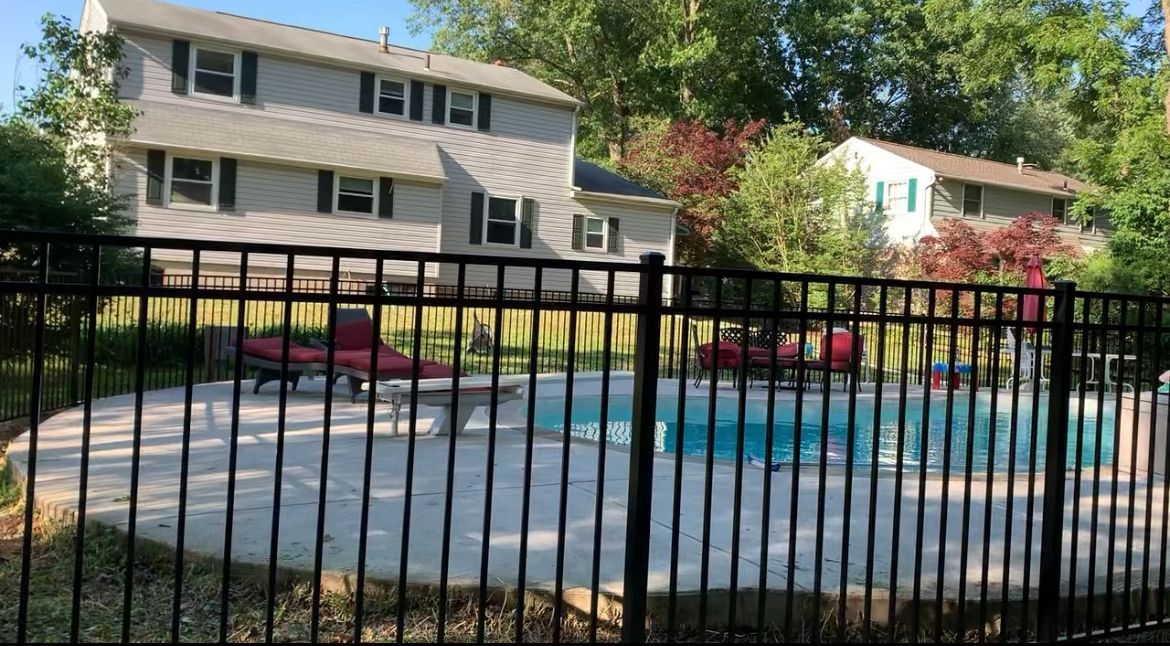 Apartment complex courtyard with a fenced swimming pool and lounge chairs in sunlight