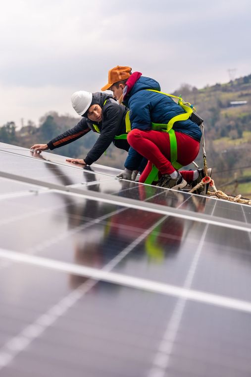 Due uomini stanno lavorando su un pannello solare in cima a un tetto.