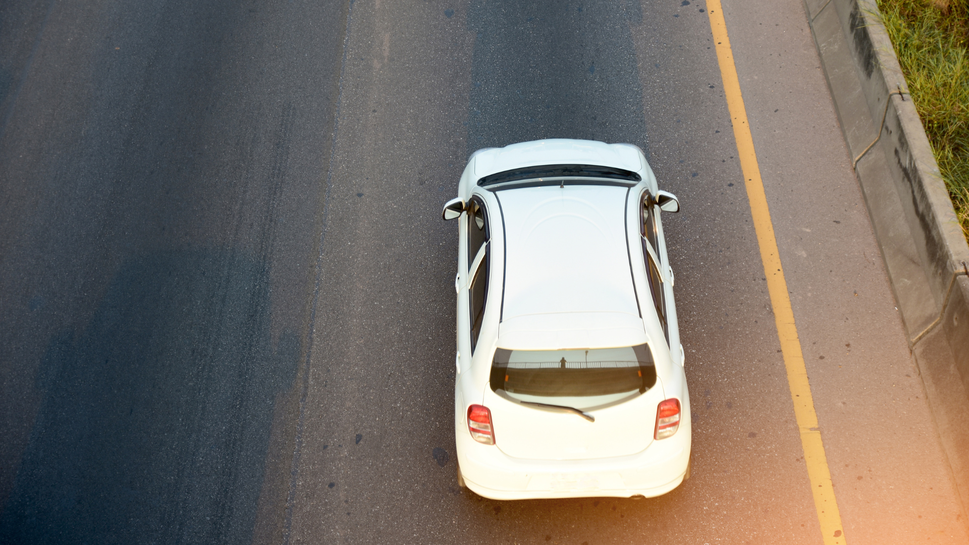 A white car is driving down a highway.