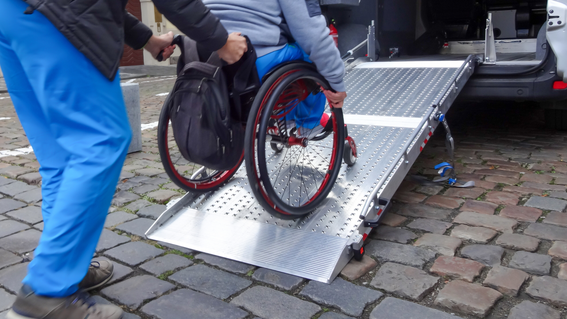 A person in a wheelchair is getting out of a van on a ramp.