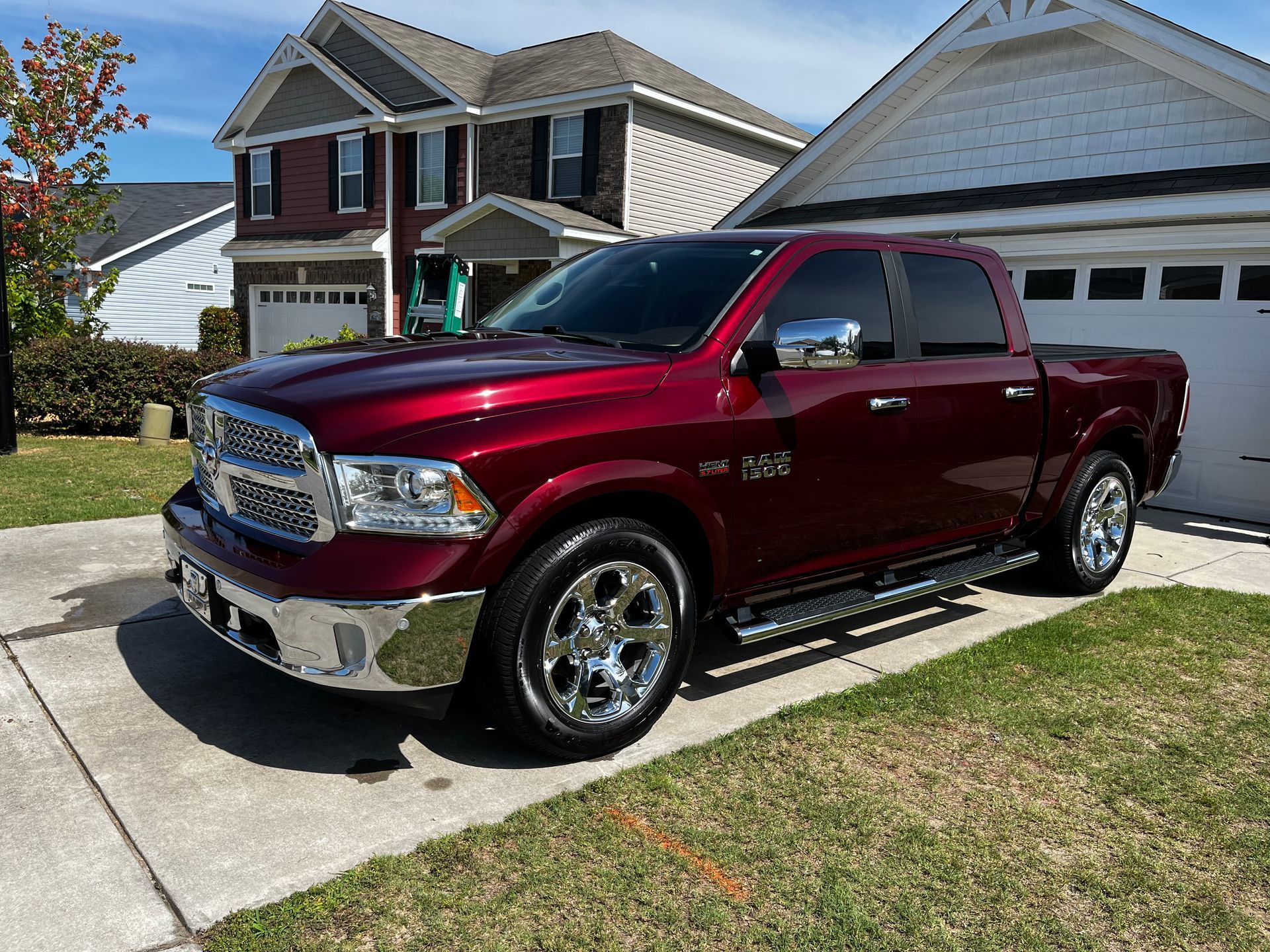 A shiny red Ram pickup truck parked on a driveway in front of a house.
