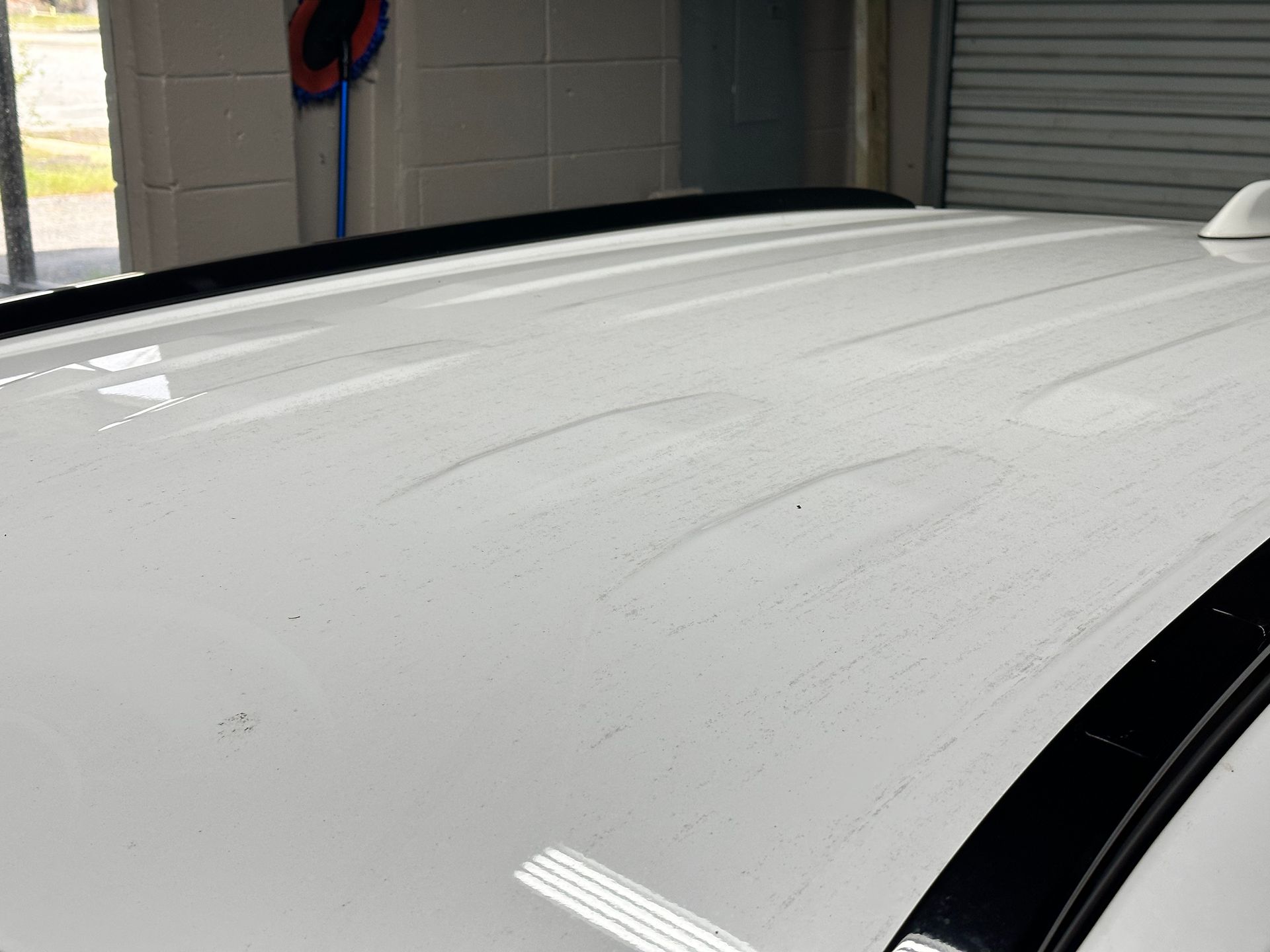 White car roof with visible water streaks and black trim, in an indoor setting.