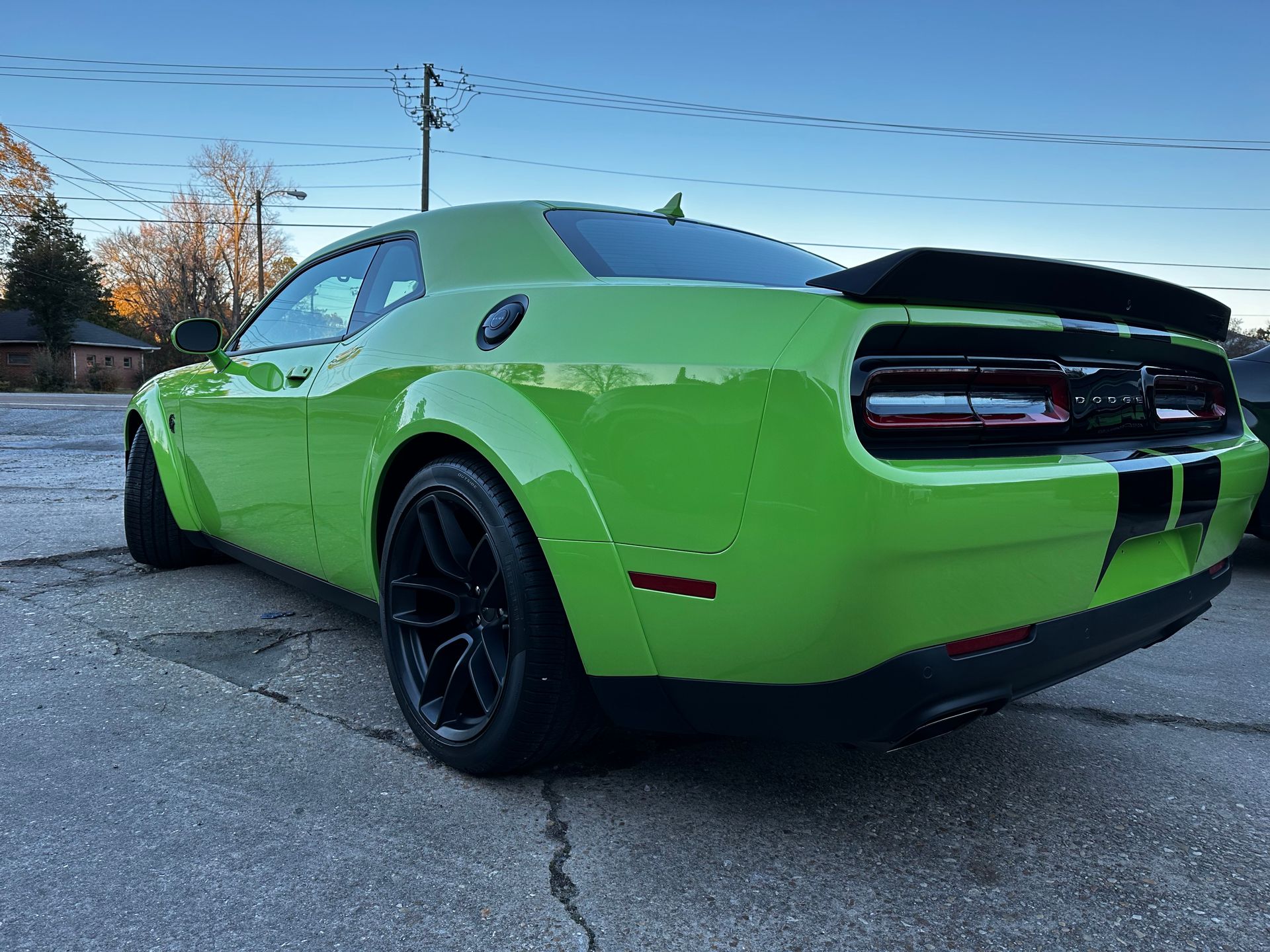 Bright green Dodge Challenger parked outdoors, rear three-quarter view, with black wheels and taillights visible