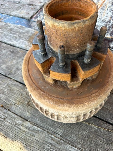 Rusty wheel hub assembly with lug bolts on weathered wooden boards