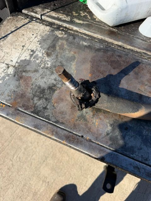 Burned metal fitting on a weathered rooftop with dark scorch marks and a hose attached