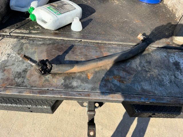 Burnt black hose or cable with a damaged end on a workbench next to a white container