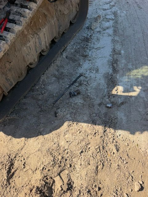 Broken asphalt road beside a dirt embankment and curb in bright sunlight