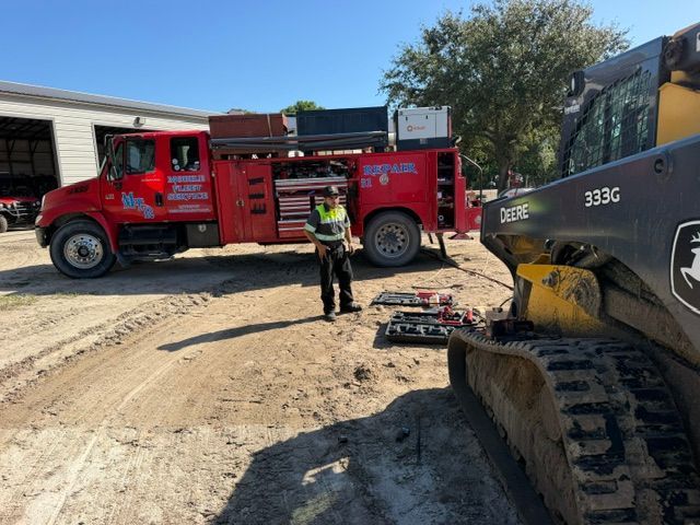 A partially disassembled heavy engine block secured on the bed of a red service truck with an attached power tool.
