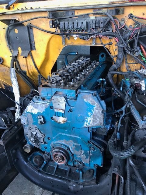 Blue diesel engine in a yellow bus engine compartment.
