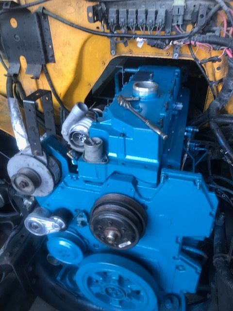 Blue engine block with attached components in a yellow compartment.