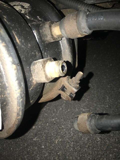 Close-up of a truck brake system. Black components and tubing with metal fittings are visible.
