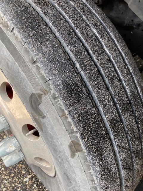 Close-up of a truck tire showing significant wear and cracks on the tread.