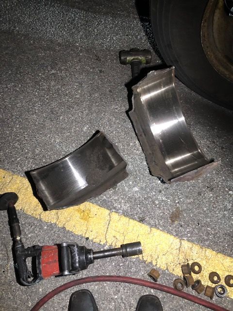 Broken metal truck bearing next to an impact wrench and tire.
