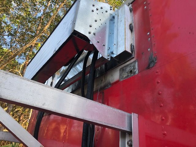 Silver metal structure attached to a red vehicle, holding black cables.