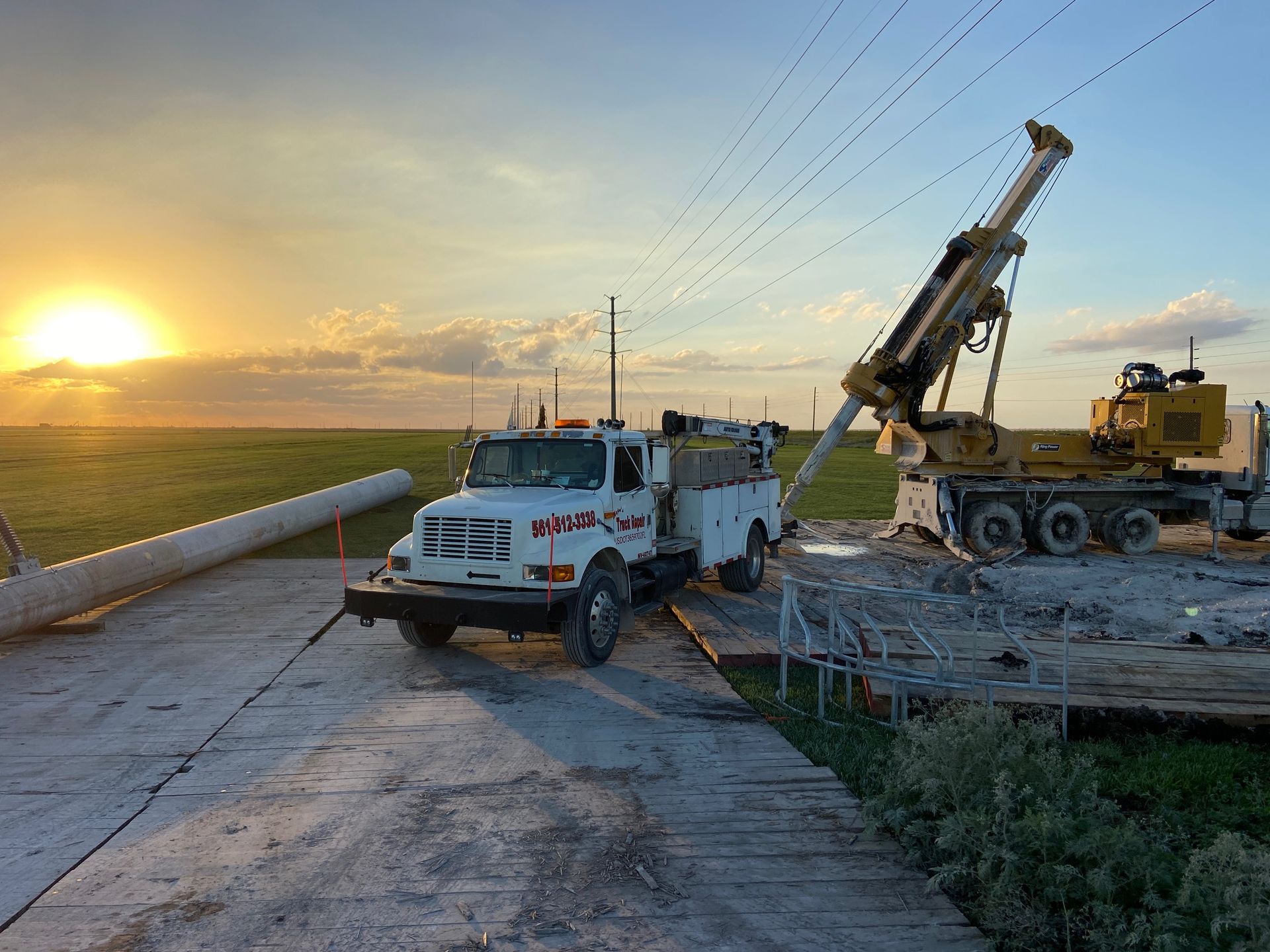 A truck is parked on the side of the road next to a crane.