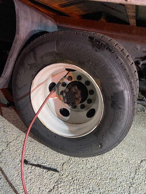Truck tire with a red hose connected to the hub. The tire is black, mounted on a white wheel.