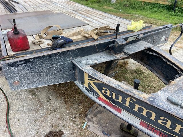 A close-up of a black Kaufman trailer undergoing repairs, various tools and materials are visible.