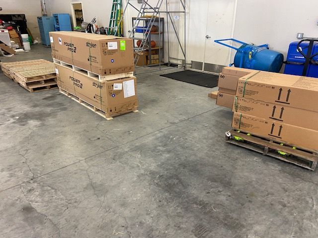 Warehouse interior with pallets of cardboard boxes on a concrete floor.
