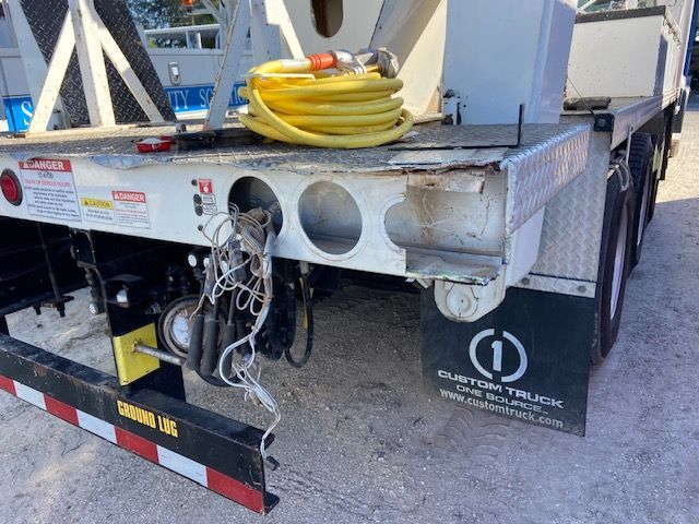 Back of a white truck trailer with yellow hose, black undercarriage, and a logo on the fender.