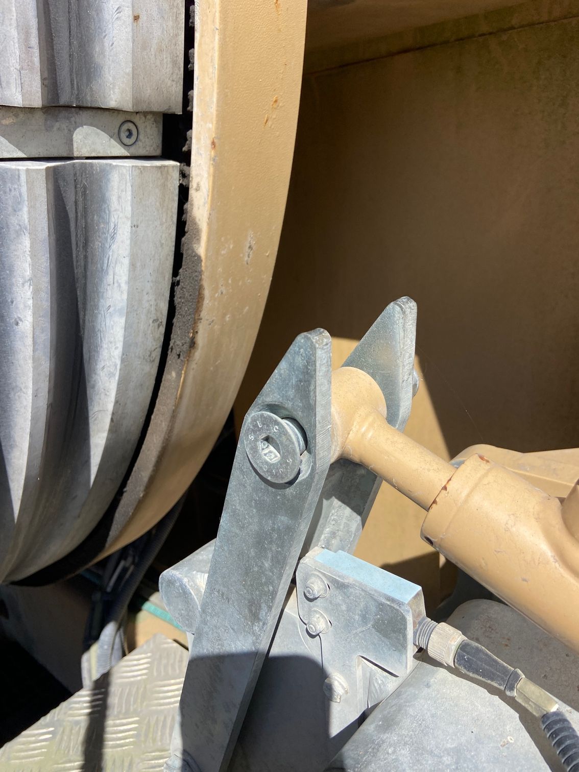 Close-up of a machine part with metal components and a beige cylindrical structure.