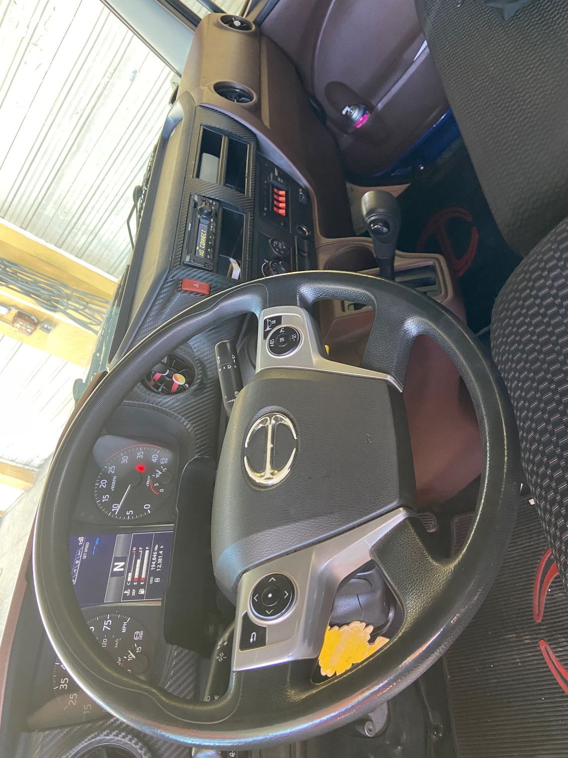 Interior of a truck cabin with a black steering wheel, dashboard, and instrument panel.