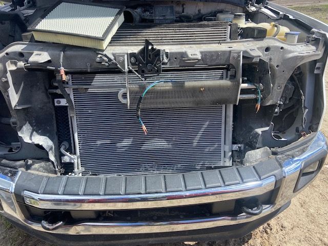Front of a truck with damaged hood and exposed radiator, air filter visible.