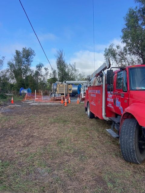 Red truck parked near well drilling equipment and safety cones outdoors.