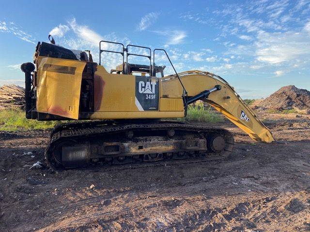 Yellow Caterpillar 345C excavator on dirt under a blue sky.