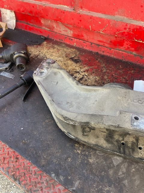 Damaged metal arm on a red surface, with debris and tool visible in a workshop.