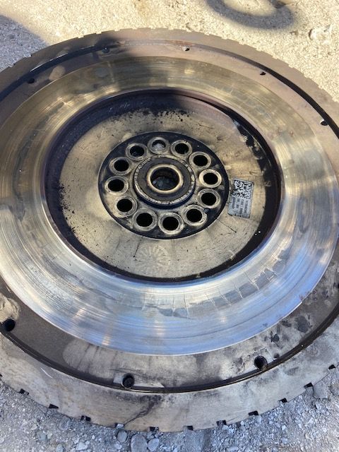 Circular, metal flywheel with wear marks and a central hub with bolt holes.