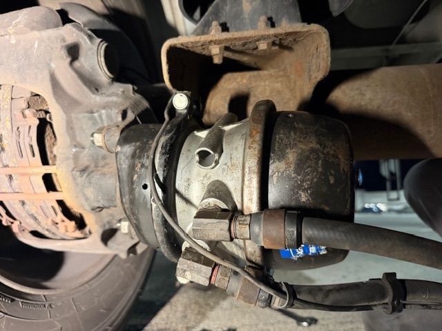 A close-up view of a vehicle's brake chamber and air brake assembly attached to the wheel hub.