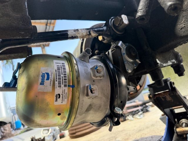 A Bendix air brake chamber mounted on a truck axle, showing the metallic housing and connected linkage components.