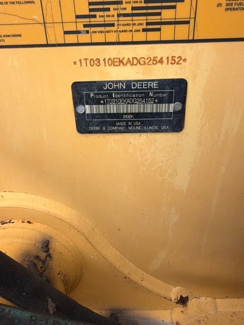 Close-up of a yellow John Deere machine serial number plate and identification label