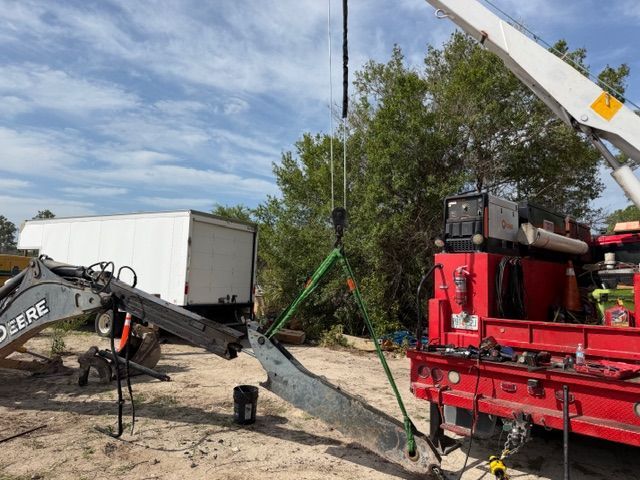 Construction equipment lifting a large concrete slab beside a red truck under a crane arm