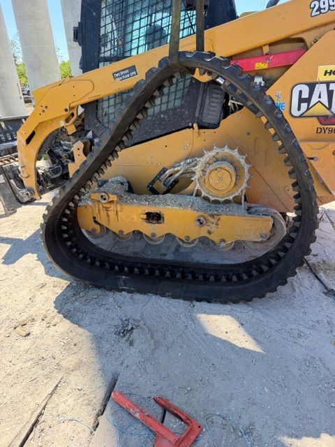 Yellow Caterpillar construction machine with a tracked wheel assembly on sandy ground.