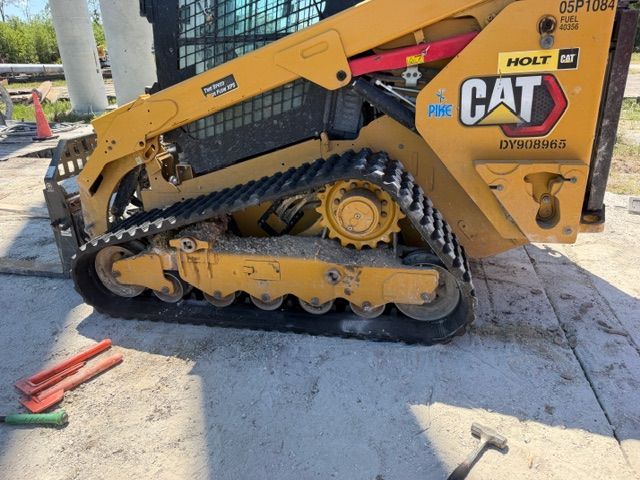 Yellow CAT skid-steer loader on tracks parked outdoors on concrete.