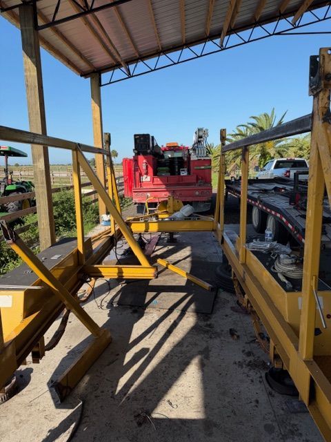 Red construction machinery under a metal shed, with yellow framework and a conveyor or lift assembly around it