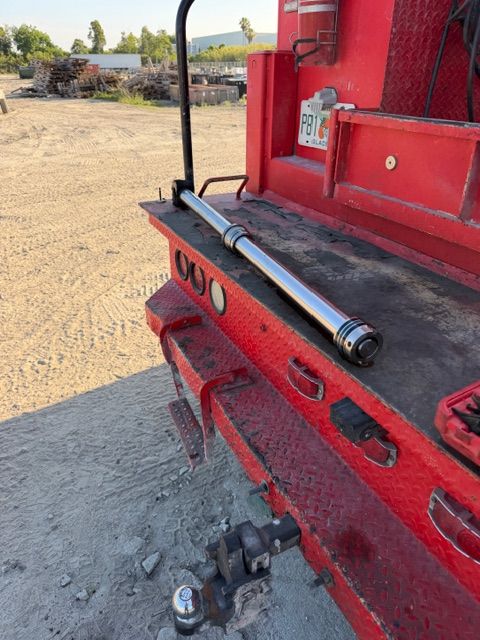 Red truck rear bumper with chrome hitch and dusty construction yard in background