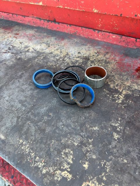 Four blue and black rubber rings beside a small metal cup on a worn concrete floor against a red wall.