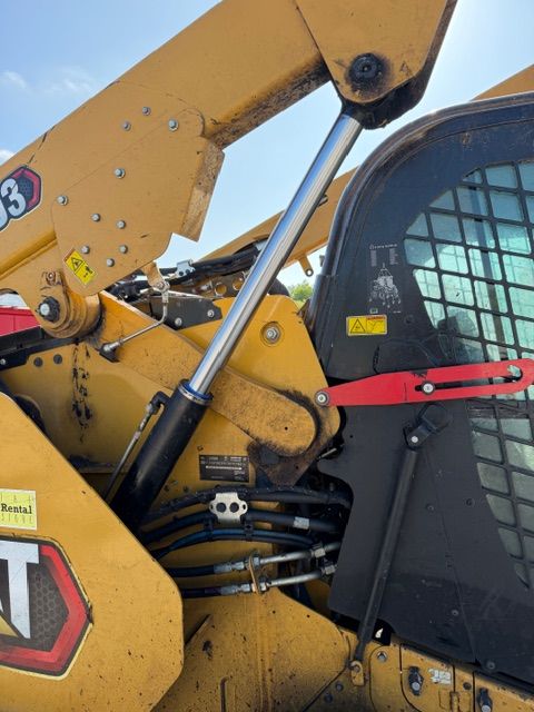 Close-up of yellow construction machinery with a hydraulic arm and black cab window grille