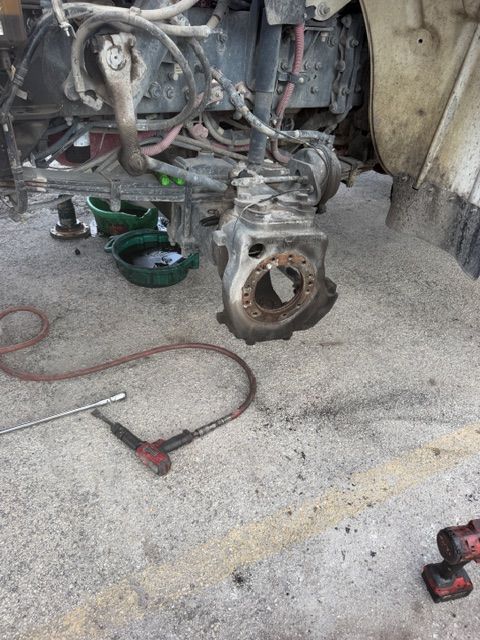 Vehicle engine removed in a garage, with tools and parts on the floor.