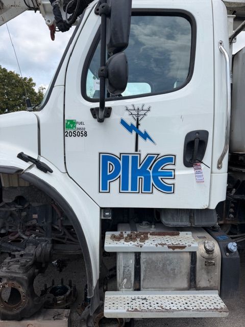 White Pike utility truck cab with damaged front wheel and steps, parked outdoors