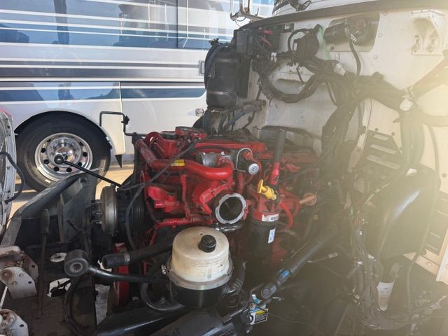 Red engine mounted in a vehicle chassis inside a garage, with a bus in the background.