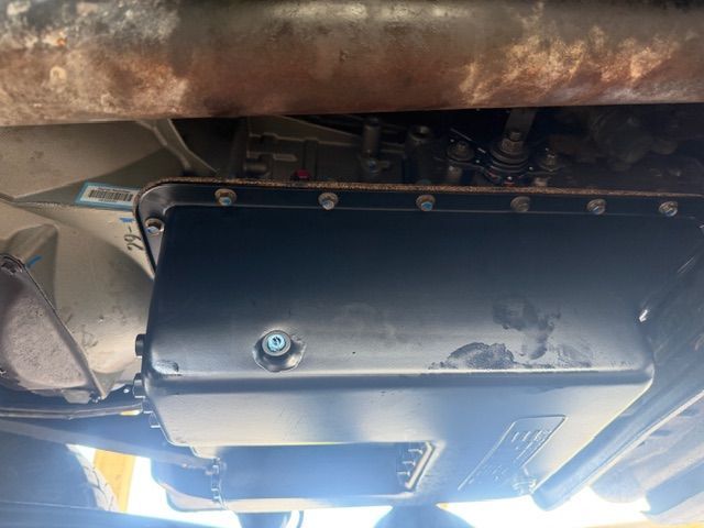 Underside of a vehicle showing a black metal box or panel mounted near the exhaust system
