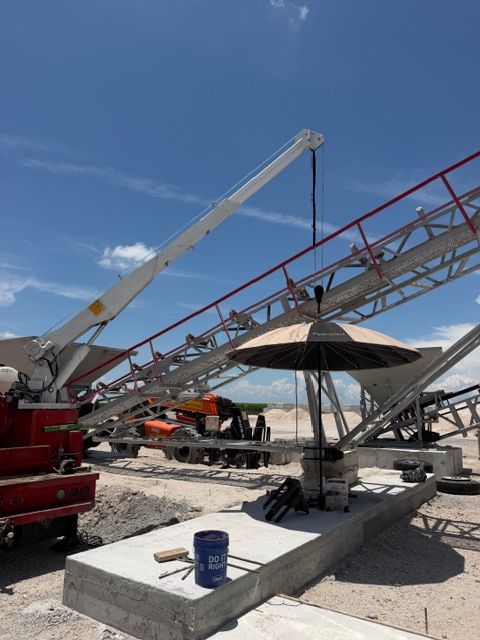 Construction site with cranes lifting a steel truss under a clear blue sky