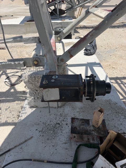 Black motor mounted on metal framework outdoors, with cables and tools nearby.
