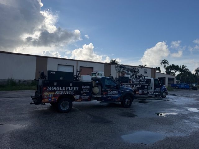 Fleet service truck with equipment parked outside an industrial building under a cloudy sky.